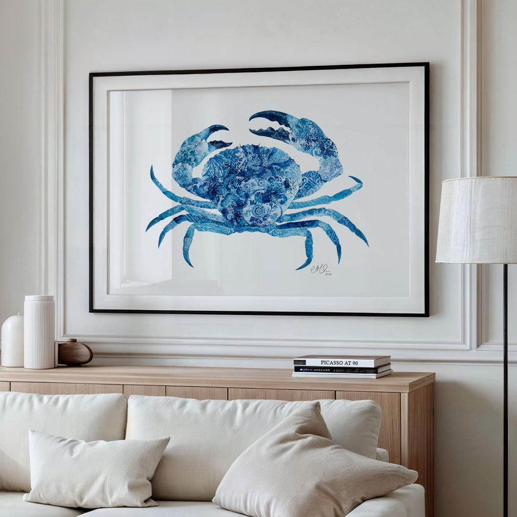 Framed artwork of a blue crab on a wall above a sofa in a living room.